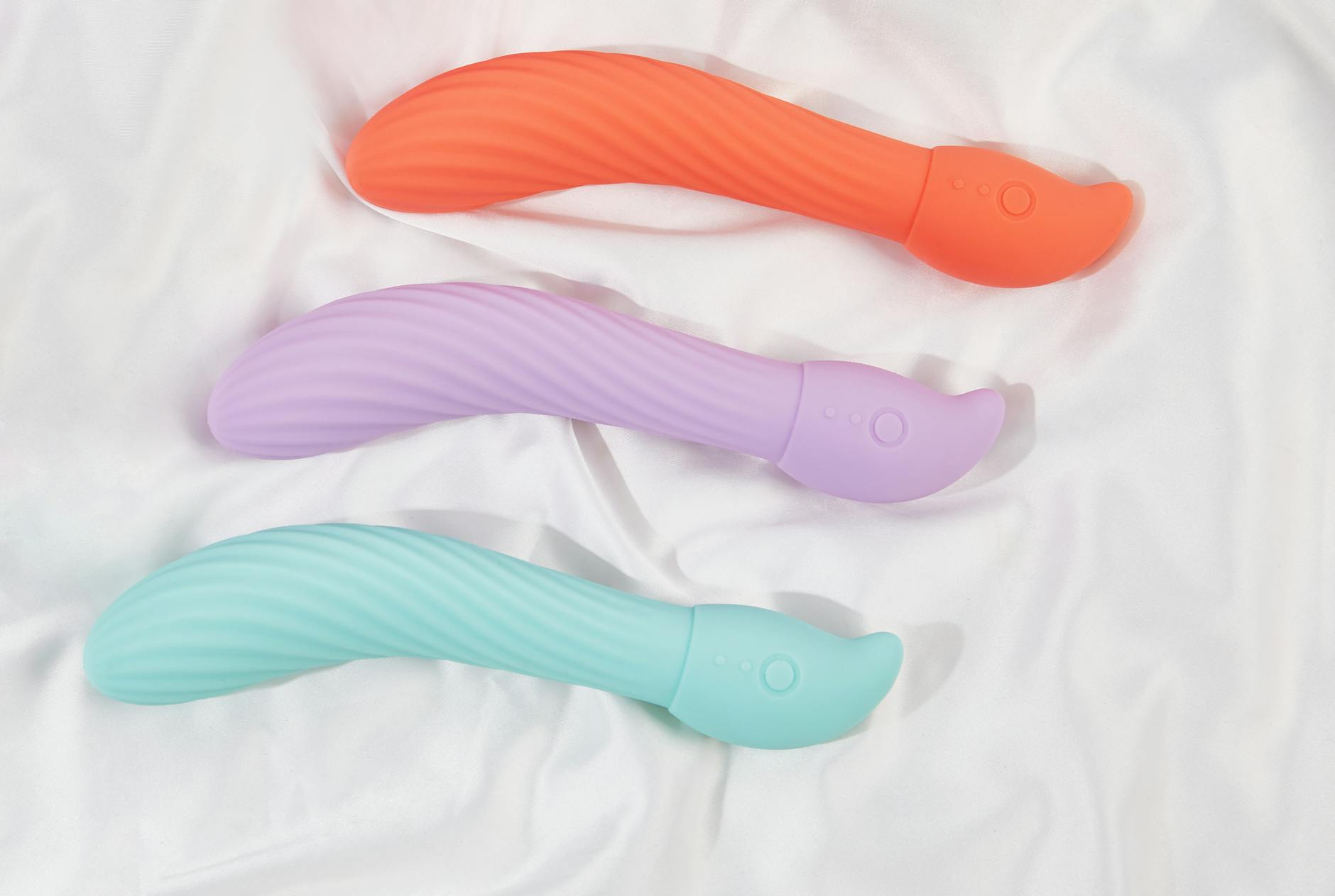 A close-up of a hand holding an orange vibrator against a minimalistic purple backdrop, showcasing modern sensuality.