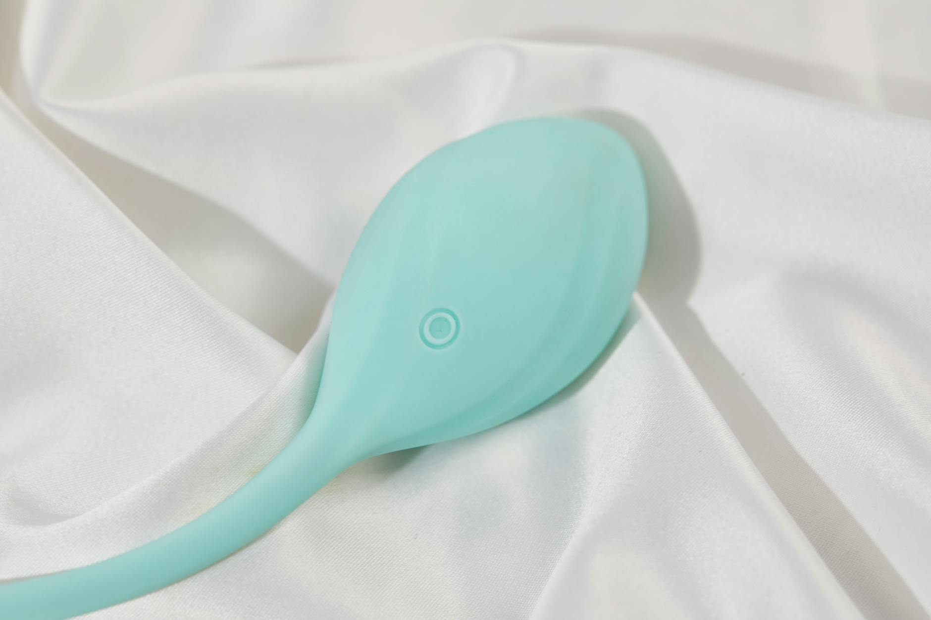 Teal lemon vibrator on white silk fabric, showcasing modern clitoral vibrator design