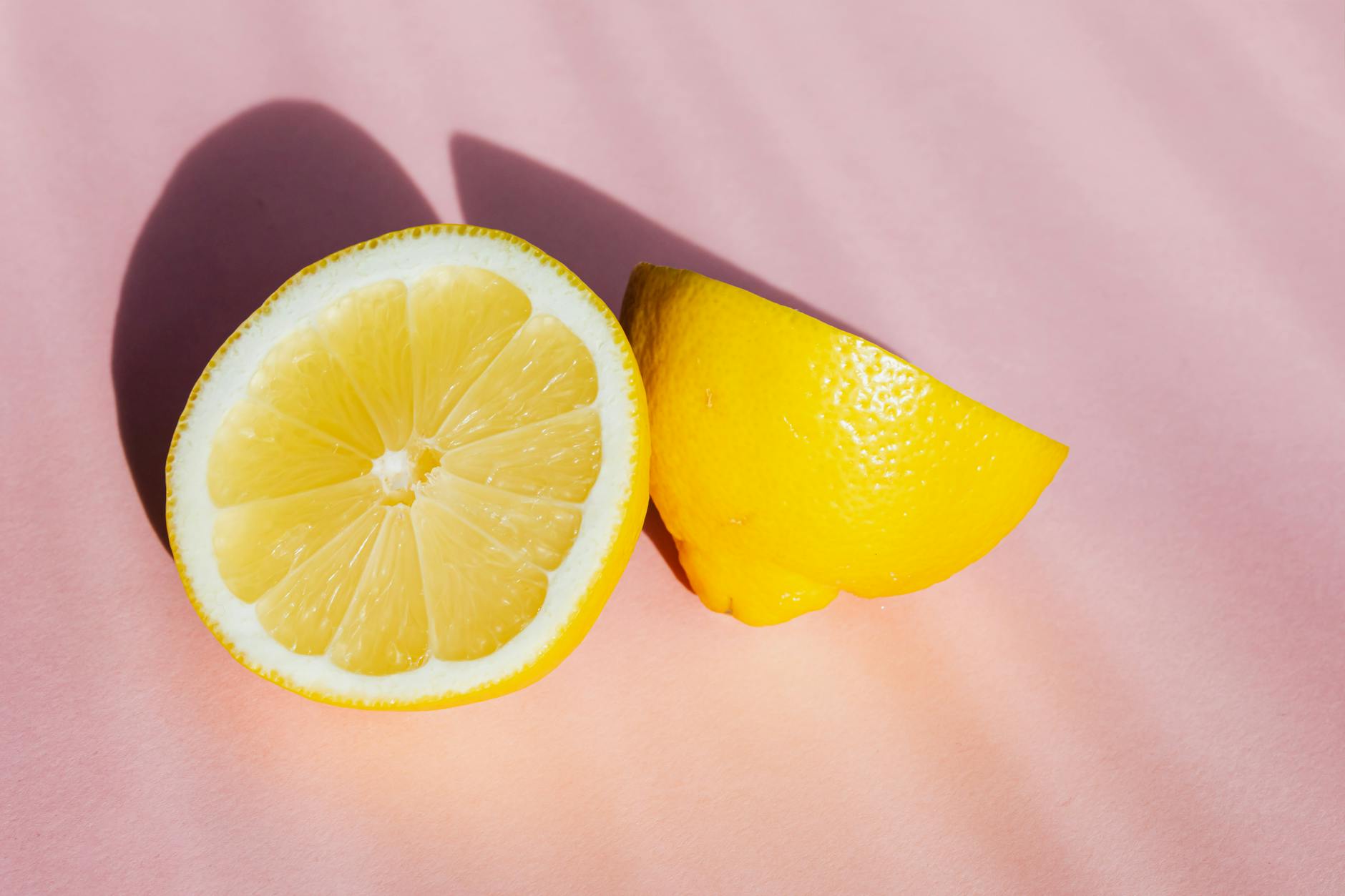 Fresh lemon halves on a pink background, representing the precision and intensity of lemon vibrators