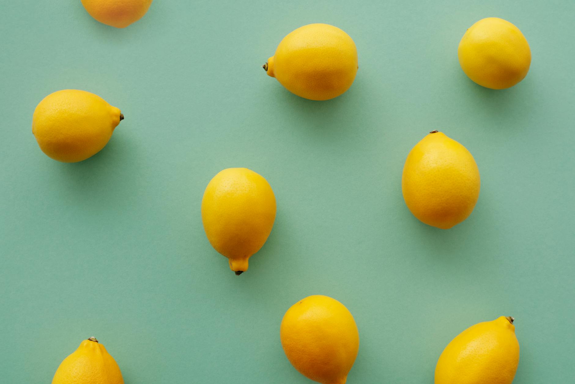 Bright yellow lemons arranged on a pastel green background, symbolizing the fresh start couples can experience with shared pleasure exploration