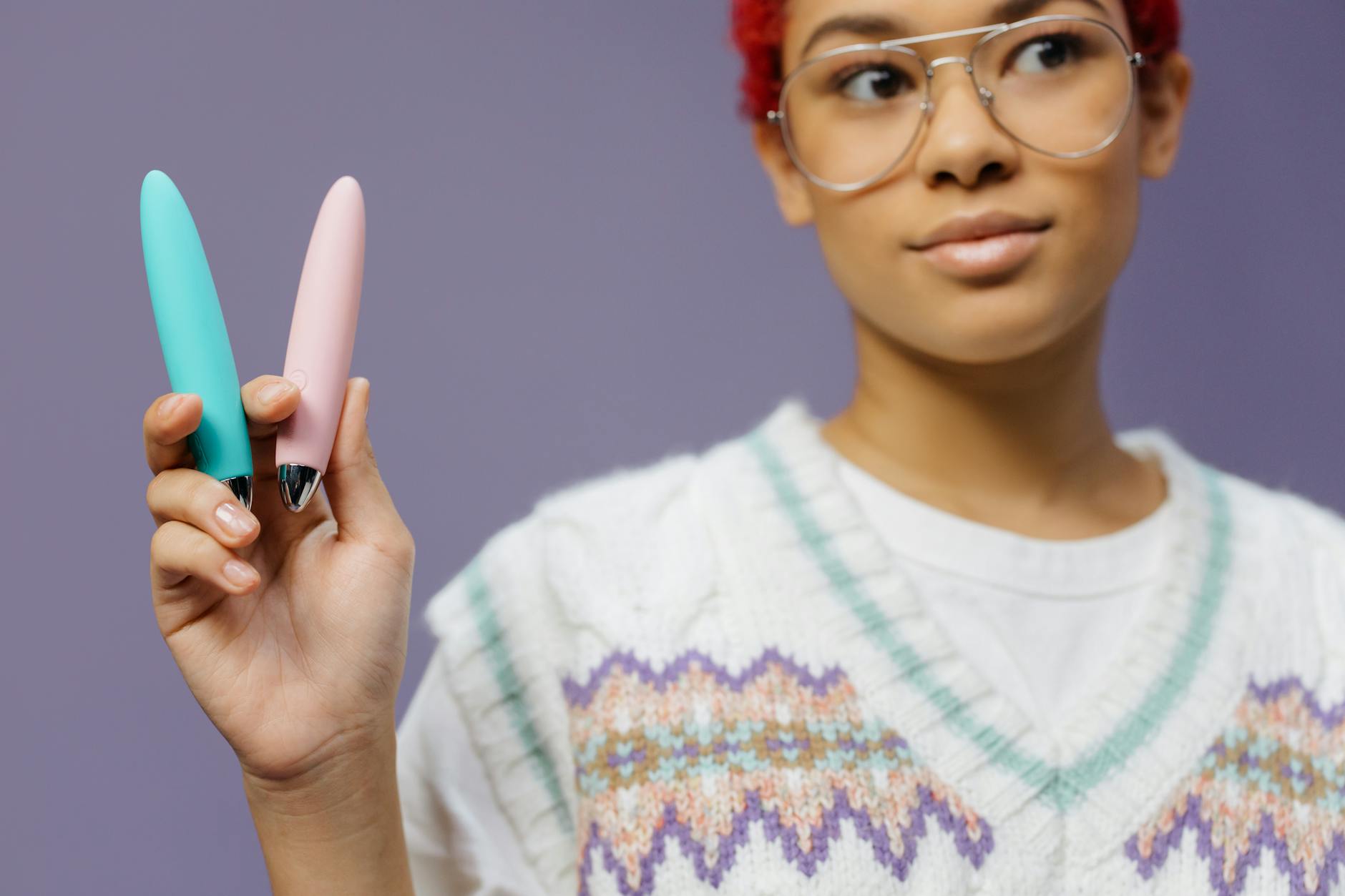 Woman holding colorful vibrators including a lemon-shaped device against a purple background