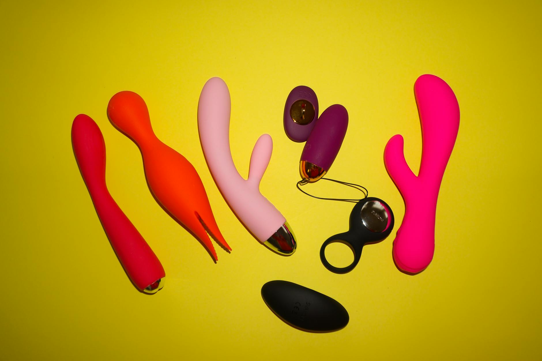 Yellow silicone lemon vibrator surrounded by fresh lemons on a yellow surface